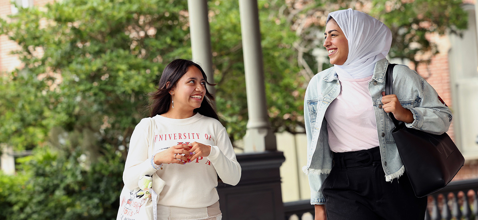 Two students walking and talking on the Plant Hall verandah.