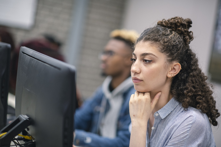 A multi-ethnic group of students are working on a university assignment. They are researching potentials for their thesis.  They are wearing casual clothes. The room is located on the university campus.