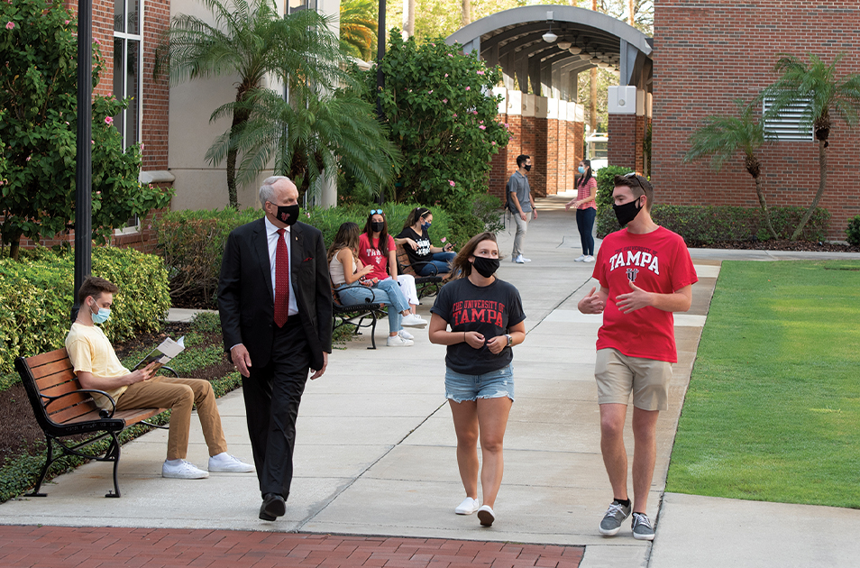 UT PRESIDENT VAUGHN WALKING WITH STUDENTS ON CAMPUS. THEY ARE WEARING MASKS.